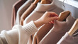 © Sayed - A person examining a collection of pastel-colored sweaters on a rack