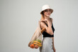 © Volodymyr_sh - Stylish woman carrying reusable net shopping bag with groceries, eco friendly lifestyle and zero waste concept isolated on light background