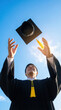 © artem - Joyful graduation celebration with cap toss under clear blue sky
