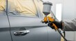 © rdkcho - Professional holding a spray paint gun ready to refinish the body panel of a car in a paint booth.