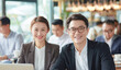 © Surachetsh - An Asian man and woman in professional clothing stand beside office equipment in warm indoor lighting, with chairs shelves and documents around them.