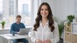 © Vasiliy - Portrait of a smiling young professional businesswoman in a modern office. Confident female leader or manager looking at the camera with a colleague in the background
