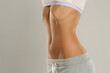 © vladimirfloyd - Side view of a woman’s torso with toned abdomen and slim waist, studio shot on a gray background