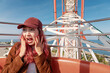 © EdNurg - Young woman feeling surprised and expressing shock on a high ferris wheel, enjoying an amusement park ride
