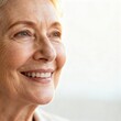 © Ardi - Close up of a smiling senior woman with fair skin and blonde hair looking at something bright.