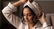 © Halyna - Young woman adjusting a beige silk hair wrap on her head. Female wearing satin bonnet and matching pajamas for hair care. Beauty routine and sleepwear concept