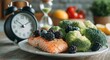© LuDo - A plate filled with healthy foods and a clock signify the schedule of intermittent fasting meals