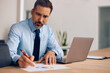 © Drazen - Male CEO working on business reports in office.