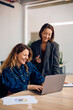 © Drazen - Happy businesswomen cooperating while working on laptop in office.