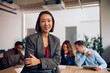 © Drazen - Happy Korean CEO having meeting with her business team and looking at camera.