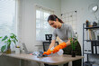 © Laingzaifa - A smiling housewife wears gloves while cleaning the house, maintaining cleanliness, hygiene, service, and a comfortable living space within the home.