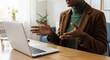 © abu - A woman in a brown blazer is talking at a laptop on a wooden desk in a bright office, showcasing online communication and business in a modern workplace setting.