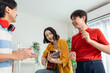 © Kawee - Diverse Asian friends playing guitar and dancing in living room at home.