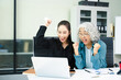 © Nuttapong punna - Asian businesswomen celebrating success in modern office. Teamwork, leadership, mentoring and collaboration concept with laptop and tablet.