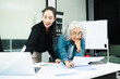 © Nuttapong punna - Asian businesswomen reviewing documents in modern office. Mentoring, consulting and teamwork concept with laptop and tablet. Corporate collaboration
