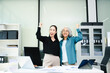 © Nuttapong punna - Confident Asian businesswomen standing in modern office. Leadership, teamwork, mentoring and corporate success concept with laptop and documents.