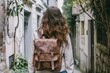 © nsit0108 - Stylish female student walking down a narrow street in a european city, wearing a leather backpack and exploring the urban environment