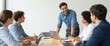 © SnapScape - Smiling Team Meeting Around Laptop at Office Table