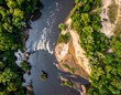 © Gas - Aerial view of river dividing sandbar, flanked by lush green forest on either side