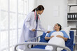 © Wasan - Female doctor is checking on a senior patient who is recovering from surgery in a hospital room.