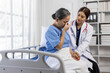 © Wasan - Young female doctor comforting a sad senior patient sitting on a hospital bed, expressing empathy and compassion while providing support during a difficult time of illness and grief.