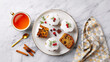 © GeanePereira - A festive holiday dessert setup with sweet bread, icing, and tea on a marble table