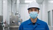 © Vasiliy - Portrait of a young Asian industrial worker wearing a white hard hat and blue face mask. Professional male engineer in a clean manufacturing facility. Workplace safety and hygiene concept