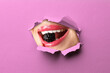 © New Africa - Young woman holding berry in mouth, closeup. View on her lips through torn hole in violet paper