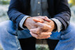 © Xavier Lorenzo - Close-up of adult man clasping hands in urban park. Still moment captured with natural outdoor atmosphere. Lifestyle and wellbeing concept.