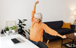 © Xavier Lorenzo - Senior adult businesswoman stretching arms and back trying to relax while working on laptop at home