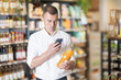 © JackF - Focused male shopper scanning barcode on juice bottle with smartphone to make mobile payment in organic grocery store. Concept of technology enhancing shopping experience