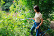 © Bluesky60 - Woman watering plants with a garden hose.