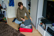© Irina Schmidt - Teenager boy packing suitcase for traveling and journey, indoors.
