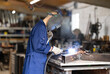 © JackF - Male welder standing with a welding semi-automatic machine and a safety helmet in a metal machining workshop