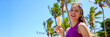 © zigres - Panoramic banner view of young woman holding popsicle ice pop on the beach with palm trees on the background. Summer holidays concept.