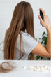 © Anna - Woman applying medical spray to her hair. Hair loss treatment and care routine