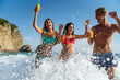 © NDABCREATIVITY - Group of young friends enjoying summer beach vacation with drinks on a tropical coastal destination