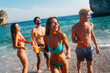 © NDABCREATIVITY - Group of young friends having fun at the beach with colorful drinks, laughing in the sun at summer