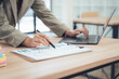© Nittaya - Business Analyst at Work: A diligent business analyst, immersed in data analysis, meticulously reviews a financial report while using a laptop to make quick decisions.