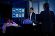 © ultramansk - Corporate executive team brainstorming a business strategy in a modern high-tech office. Professionals discussing marketing concepts written on a transparent board while using digital devices.