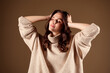 © Beauty Hero - Elegant young woman wearing a cozy beige sweater, with relaxed pose over beige gradient background