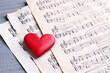 © New Africa - Heart figure and paper sheets with music notes on gray wooden table, closeup
