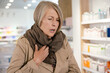 © zinkevych - Mature sick caucasian woman with a scarf on her neck at the pharmacy