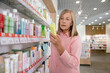 © zinkevych - Blonde good-looking mature woman in a drug store choosing something