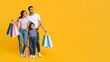 © Prostock-studio - Shopping Offer. Smiling Arab Family With Little Daughter Carrying Shopper Bags And Pointing Aside At Copy Space Over Yellow Background, Happy Parents And Female Kid Enjoying Seasonal Sales, Panorama