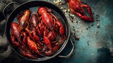Close-up of cooked crawfish in a pan, beside scattered pepper, against textured backdrop