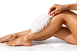 © Peahen - Wide shot of female legs brushed with feather showing skin smoothness on bright background. Concept of laser epilation advertising, dermatology testing, body care and feminine hygiene.