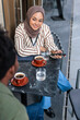 © Jovo Jovanovic/Stocksy - Woman enjoying coffee and conversation at an outdoor café