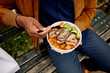 © Boris Jovanovic/Stocksy - Man eats lunch outside from a takeout box