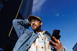 © Oleksii Syrotkin/Stocksy - Casual man with smartphone looking up outdoors against blue sky
